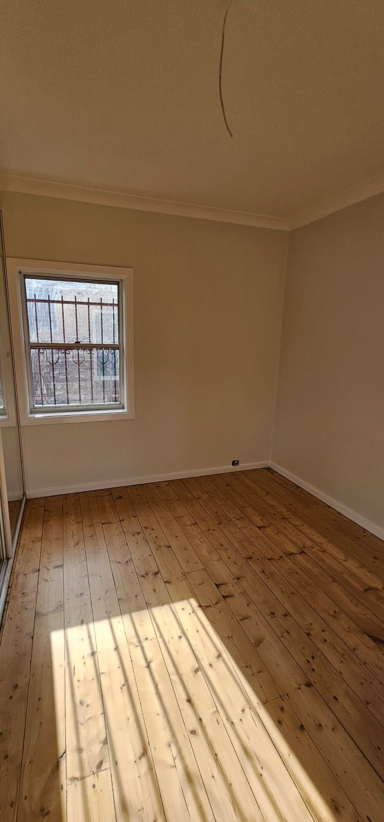 An empty room with wooden floors and a window.