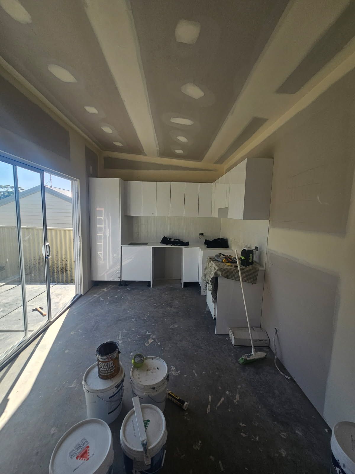 A kitchen under construction with buckets of paint on the floor