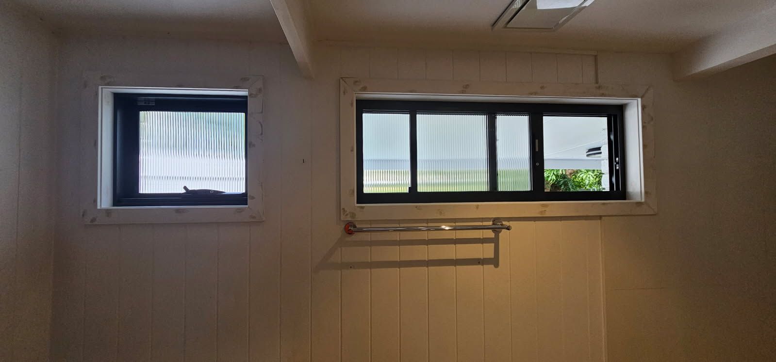 A room with two windows and a towel rack