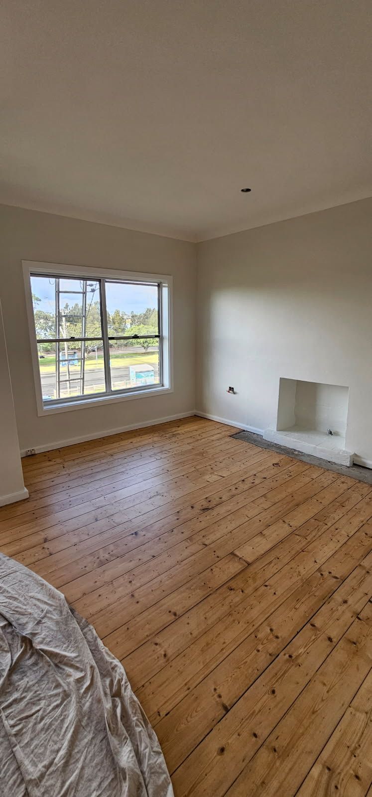 An empty living room with wooden floors and a fireplace.