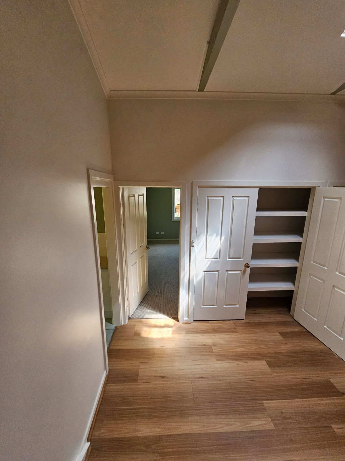 An empty room with hardwood floors and white walls.