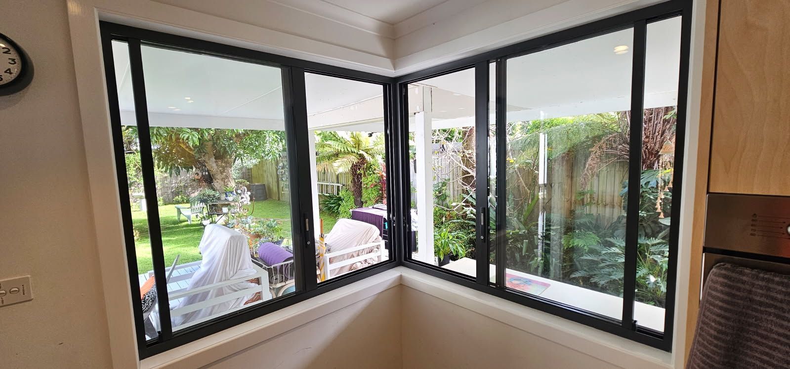 A kitchen with a lot of windows and a clock on the wall.
