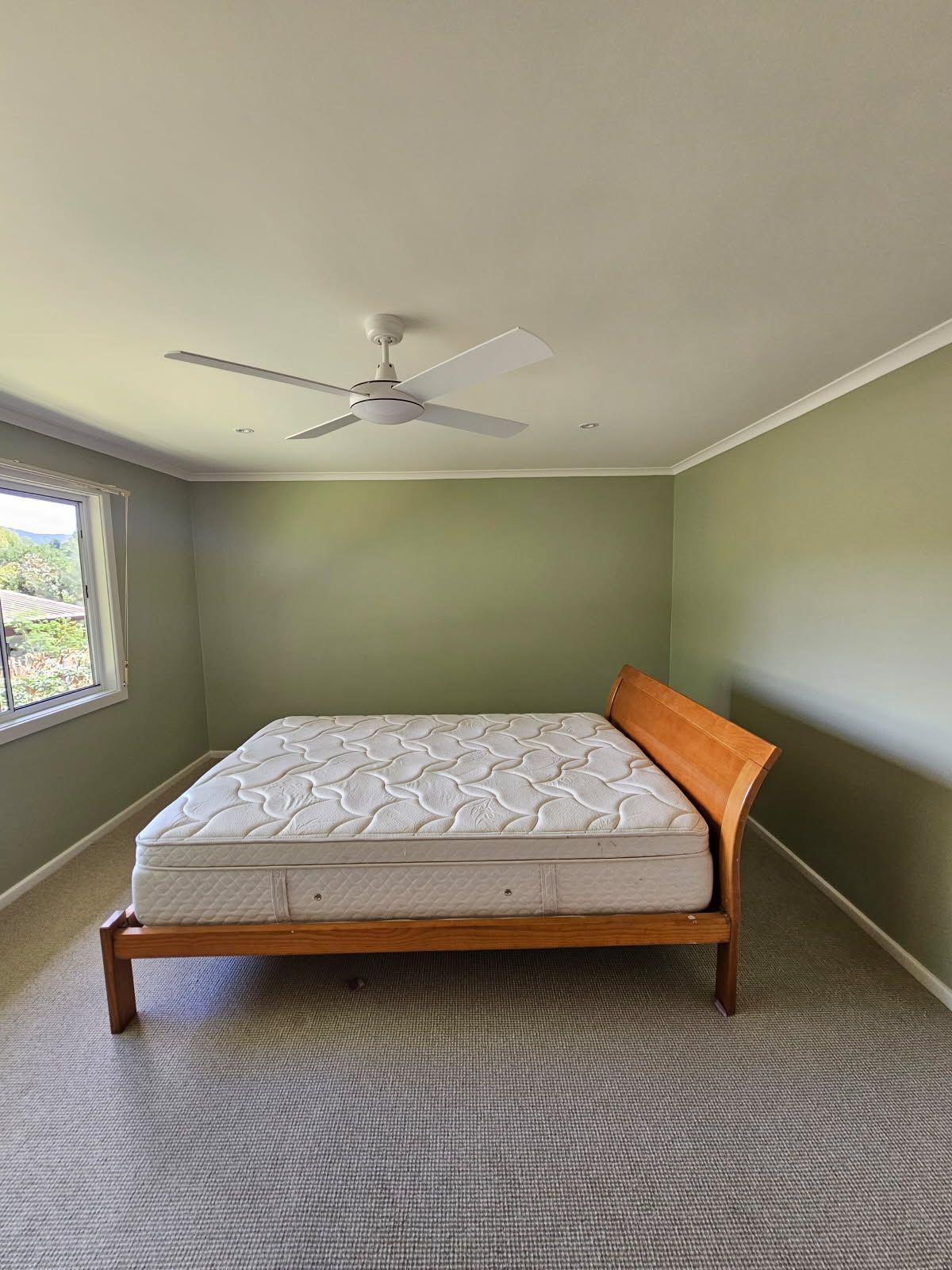 A bedroom with a bed and a ceiling fan.