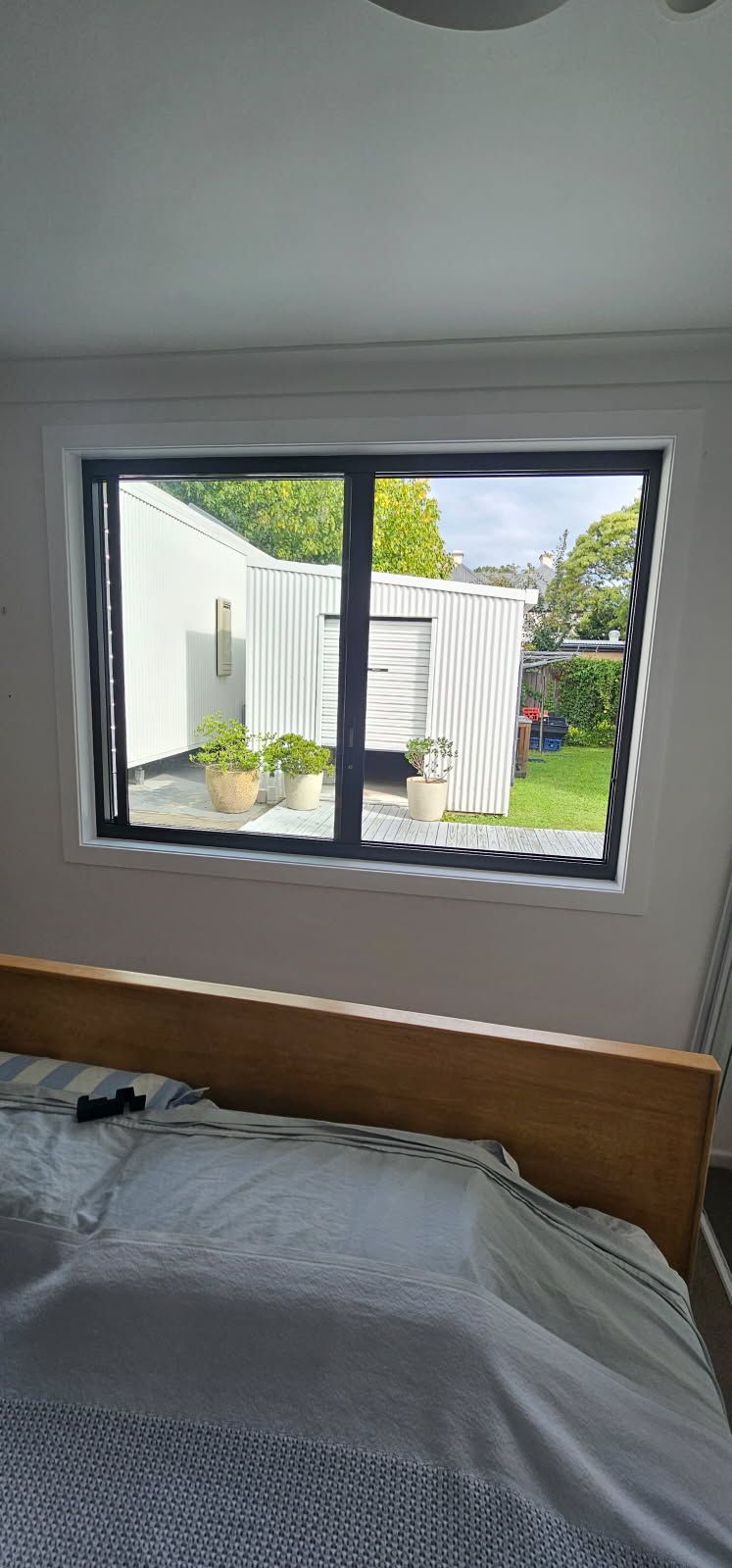 A bedroom with a bed and a window with a view of a garden.