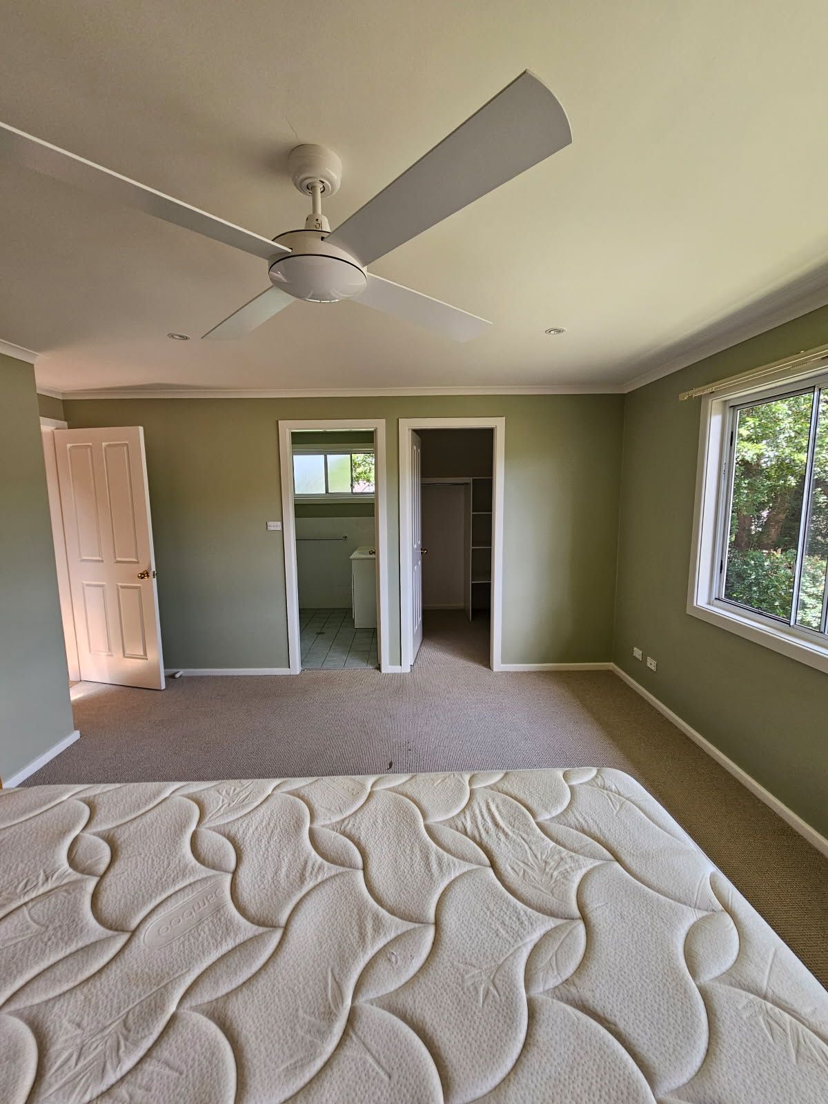 A bedroom with a bed and a ceiling fan.
