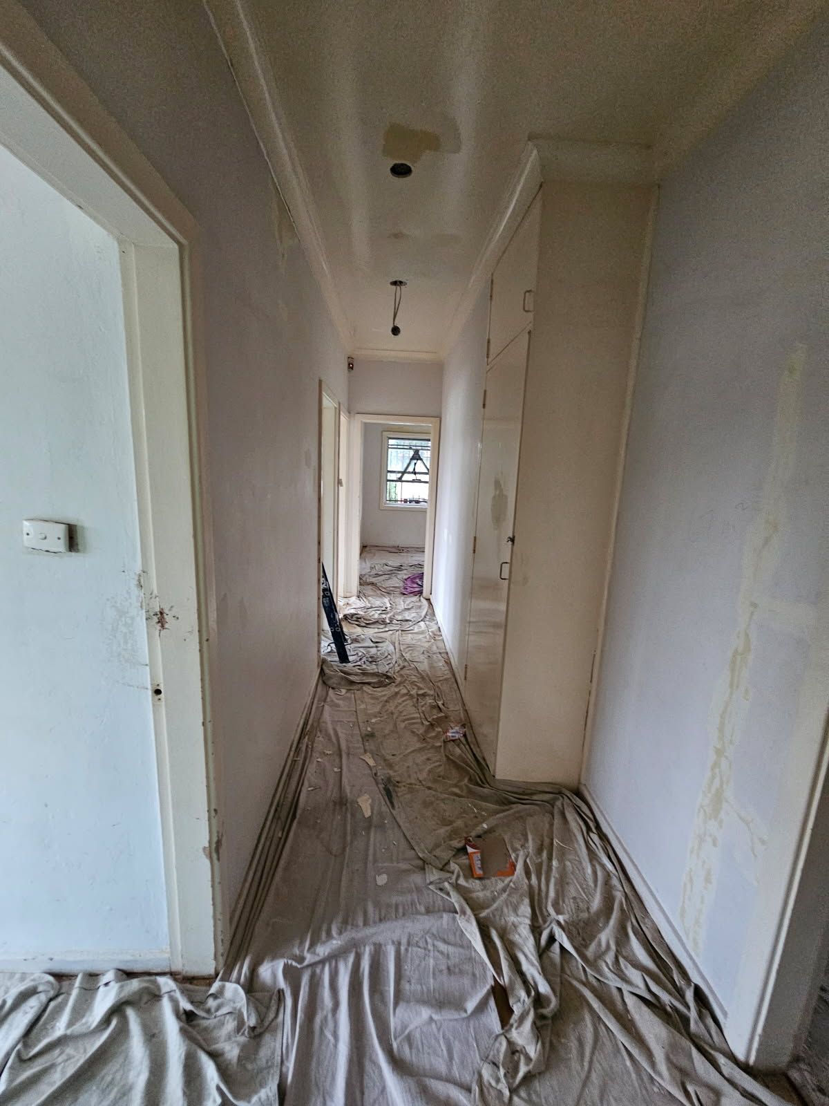 A long hallway is being painted in a house.