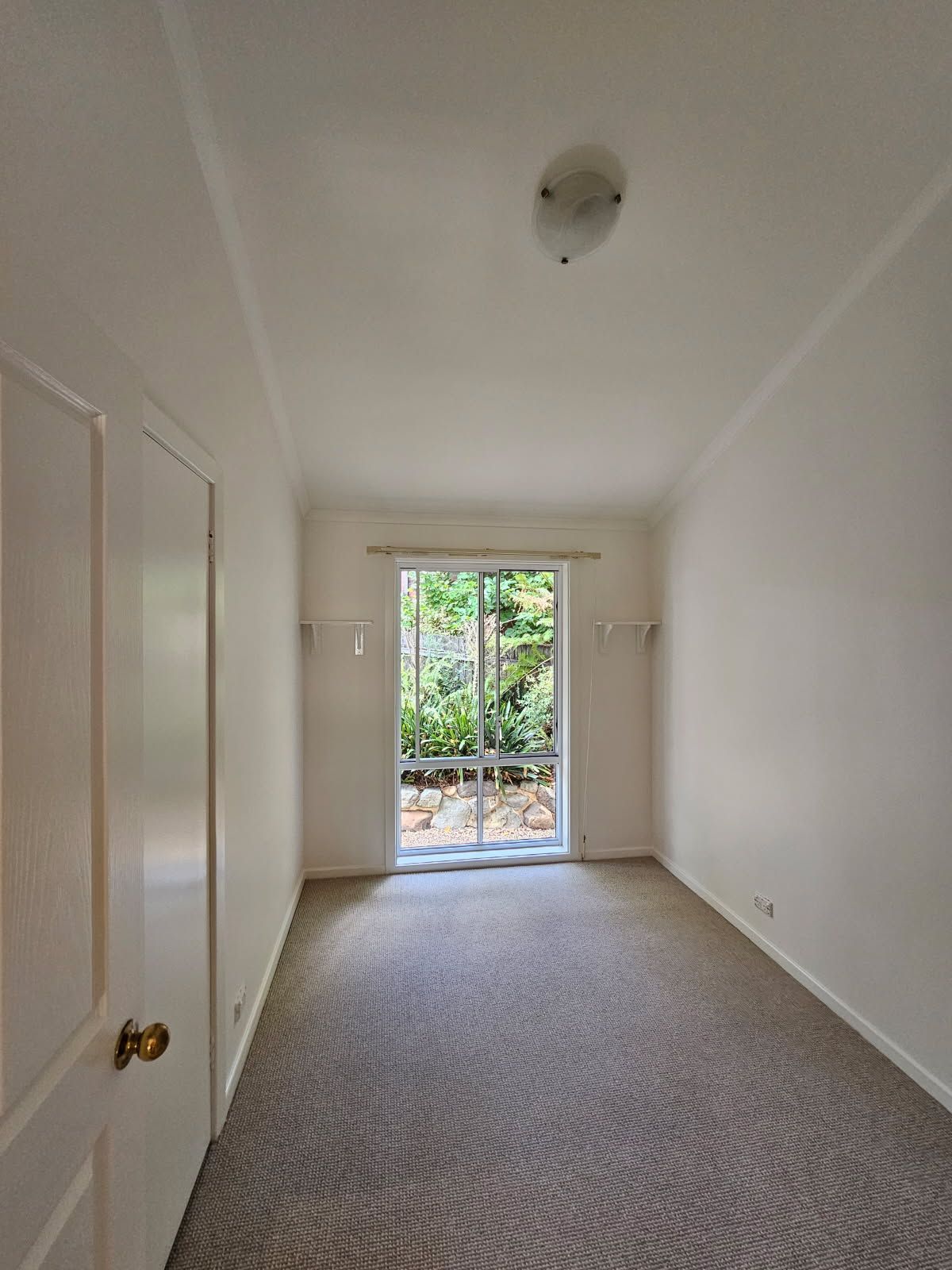 An empty room with a sliding glass door and a window.