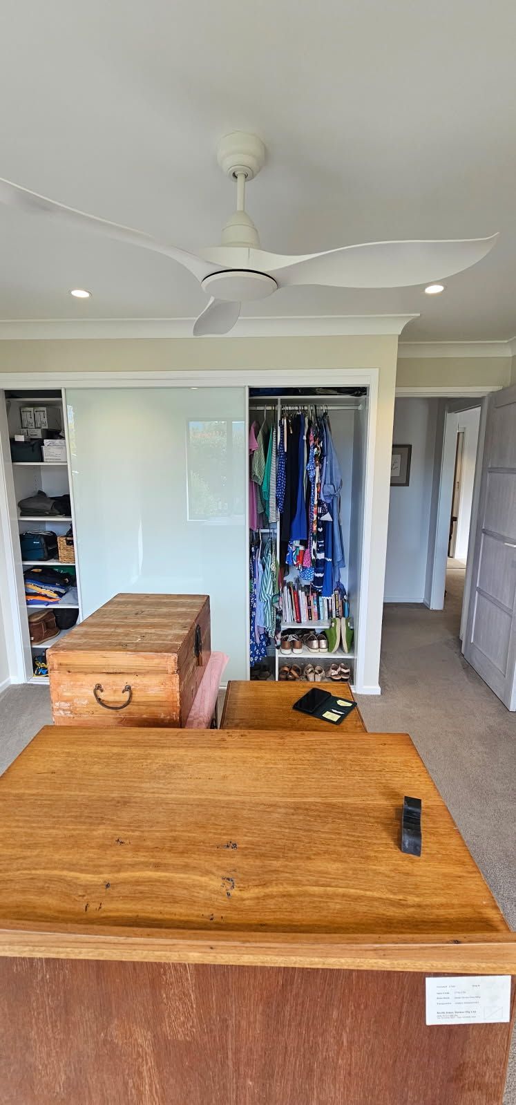 A living room with a wooden table and a ceiling fan.