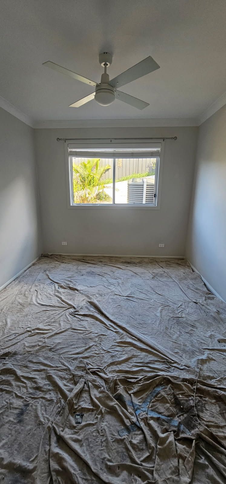 An empty room with a ceiling fan and a window.
