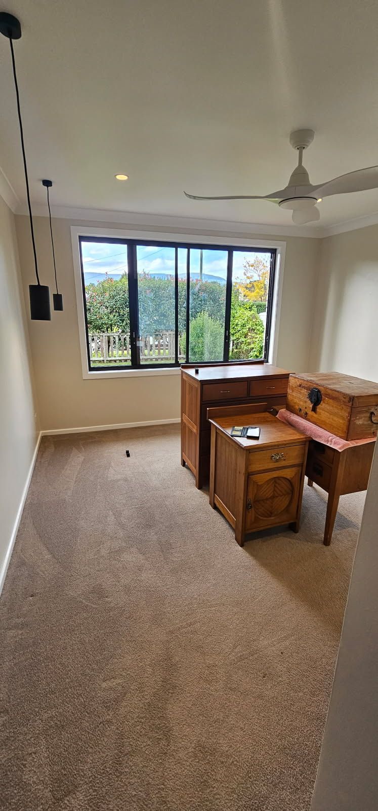 An empty room with a desk and a ceiling fan.