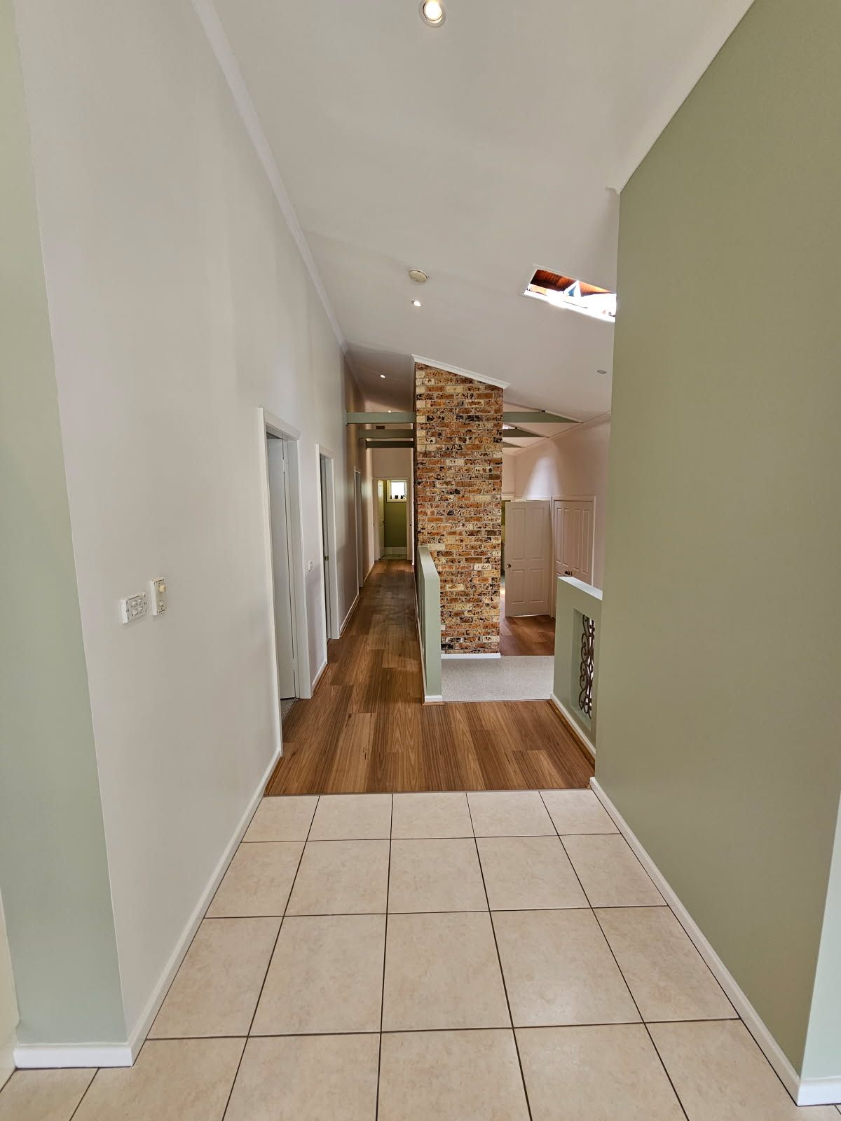 A long hallway with tile floors and a stone wall