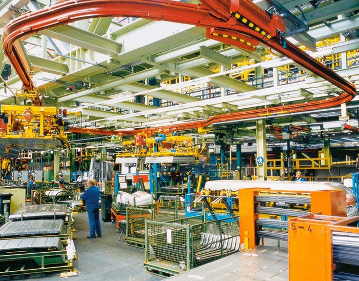 A man standing in a factory with a sign that says ' s-a ' on it