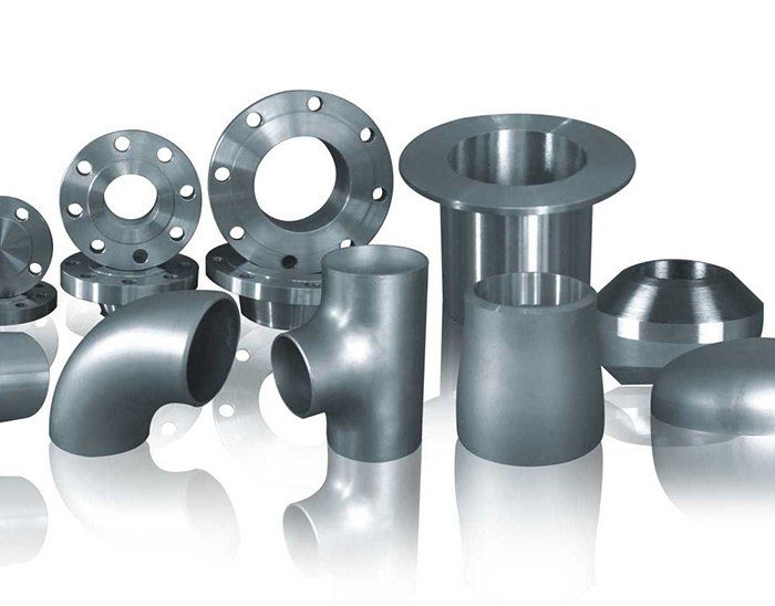 A variety of metal pipe fittings are lined up on a white surface.
