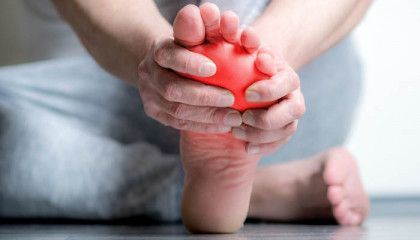 A person is holding a red ball to their foot.