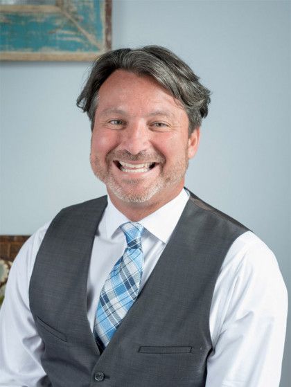 A man wearing a vest and tie is smiling for the camera.