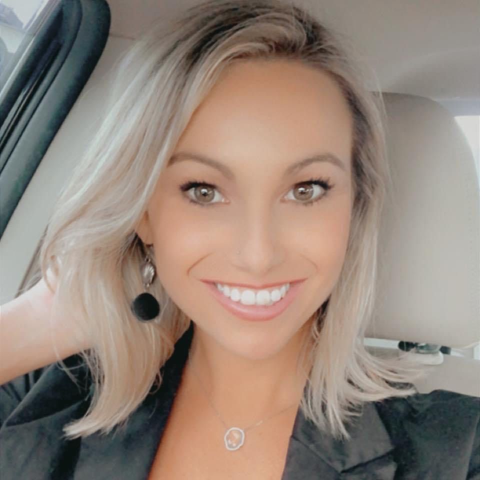 A woman is smiling while sitting in the driver 's seat of a car.