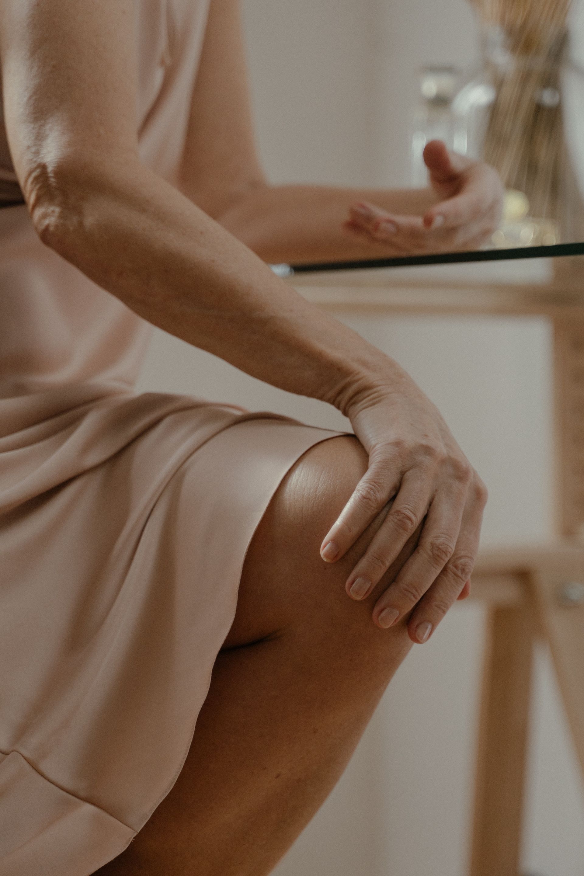 A woman is sitting at a table with her hands on her knees.