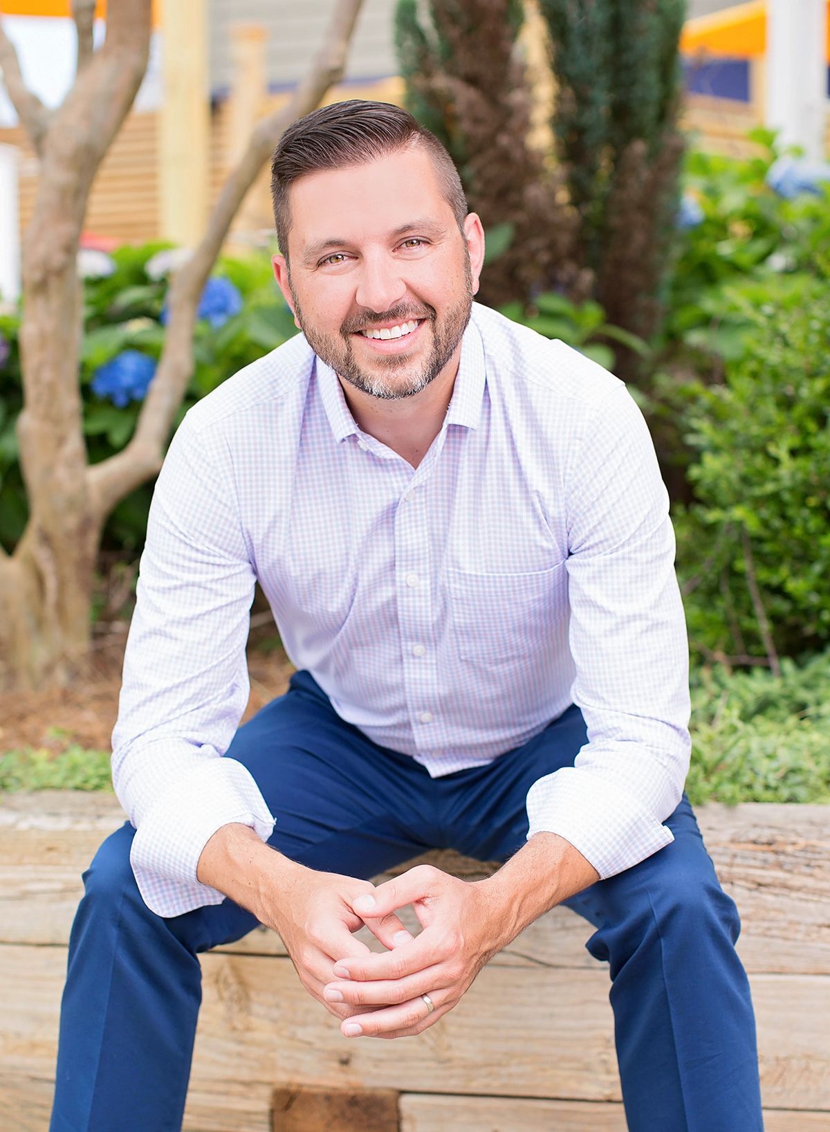 Man in blue blazer smiles, indoors, near window.