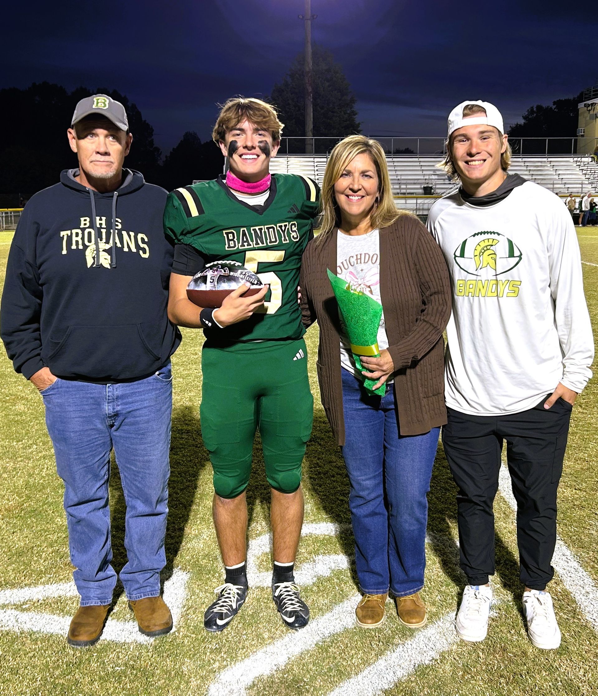 Woman with blonde hair smiles, wearing glasses, sitting indoors with fall-themed decor.