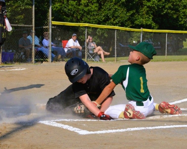 Boy in red helmet batting in baseball game, pitcher throwing ball.
