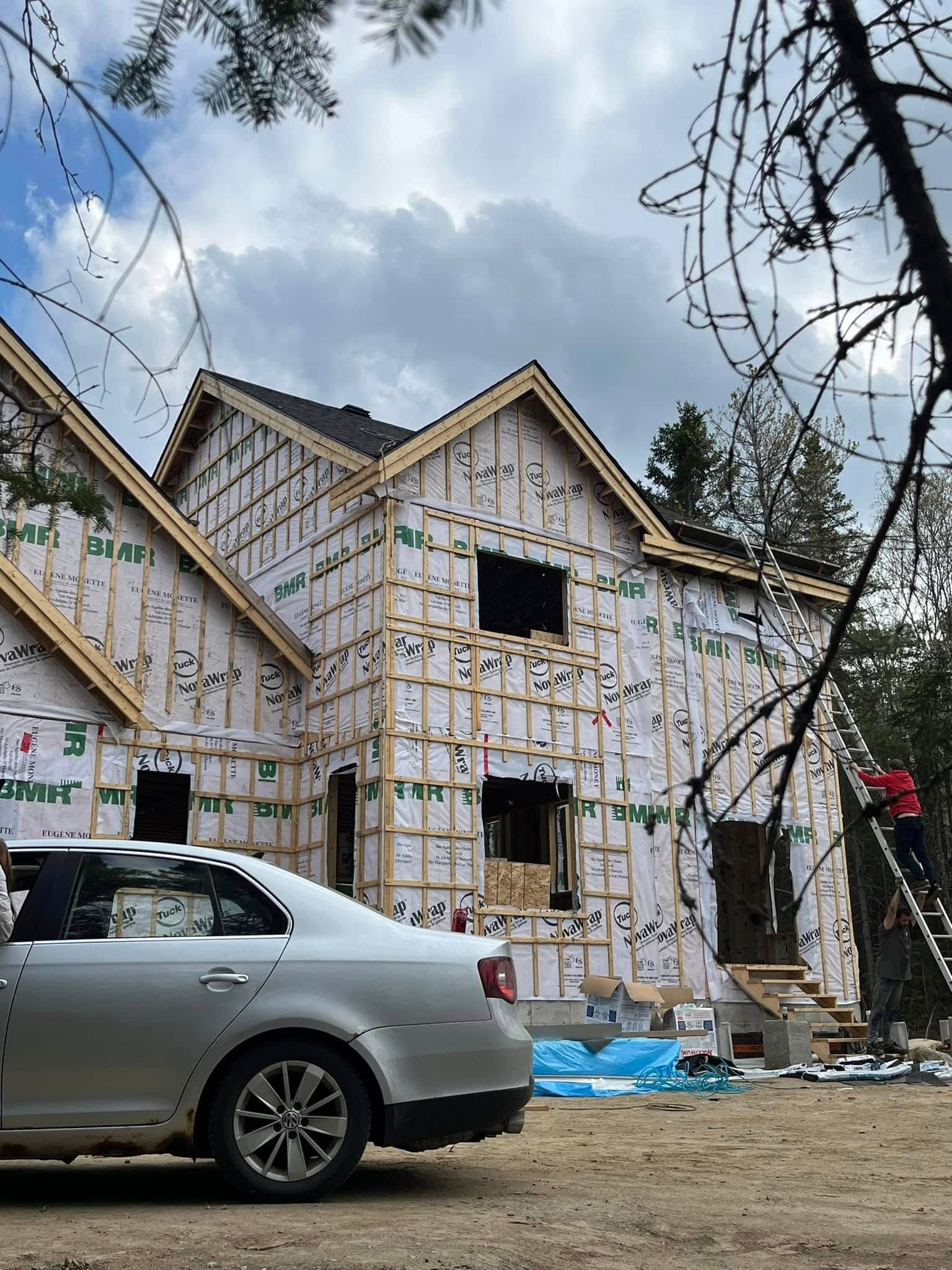 Une voiture est garée devant une maison en construction.
