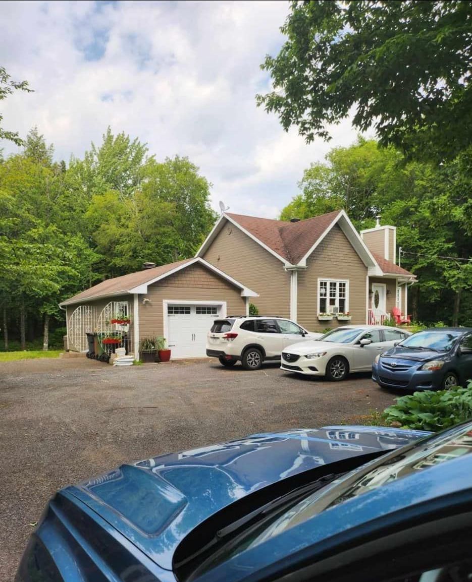Une voiture bleue est garée devant une grande maison.