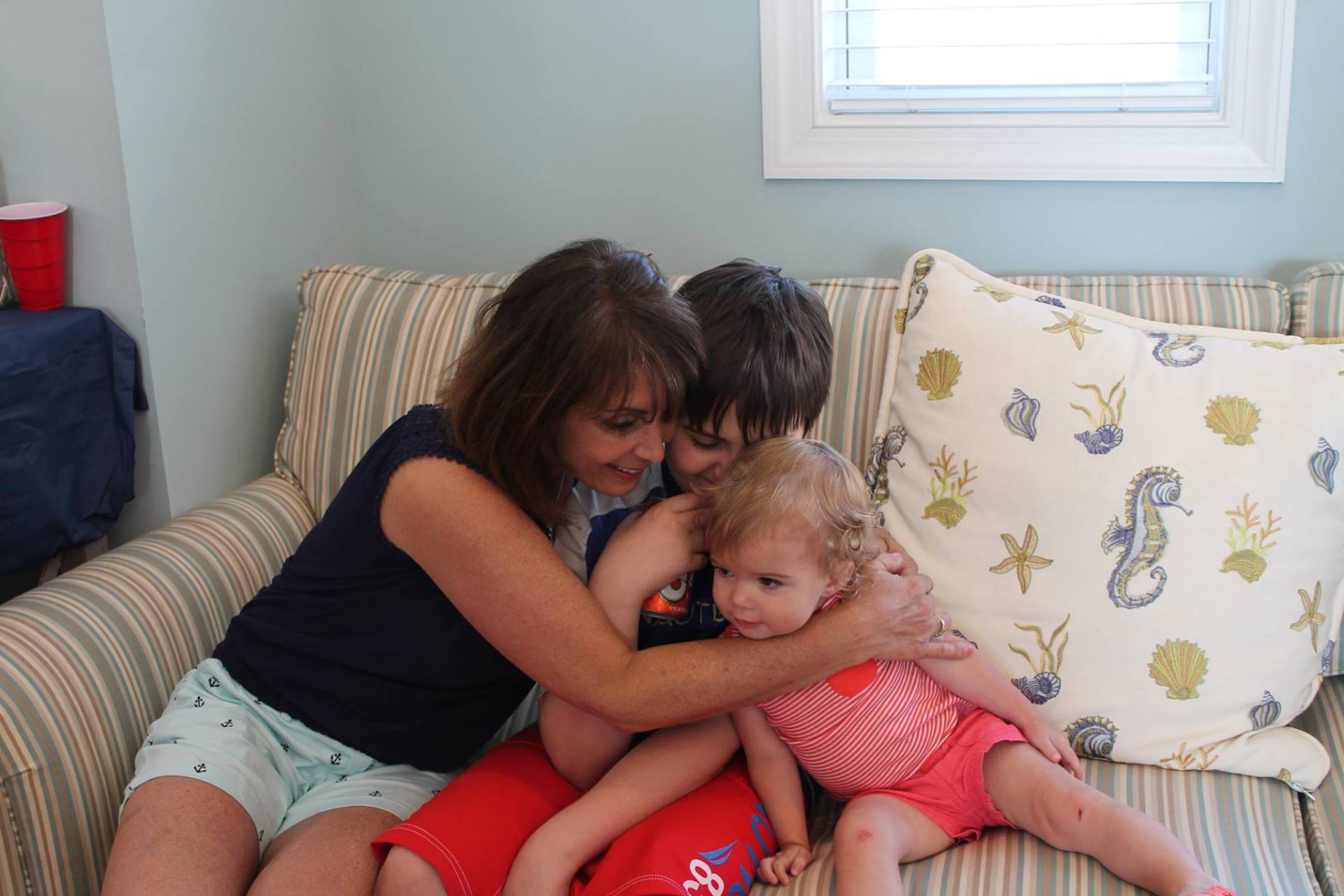 Happy family of three hugging on couch