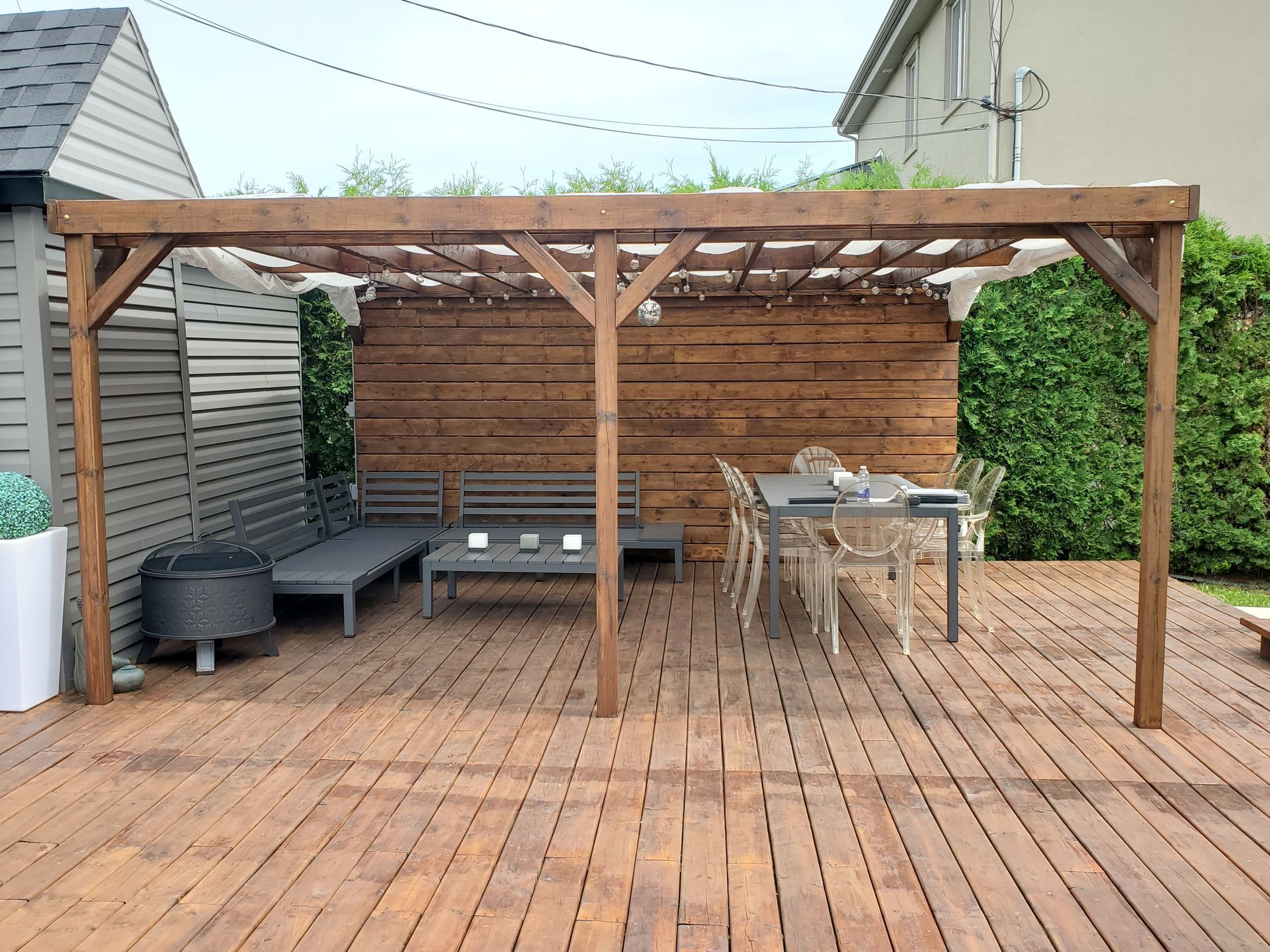 Une terrasse en bois avec une table et des chaises sous une pergola.