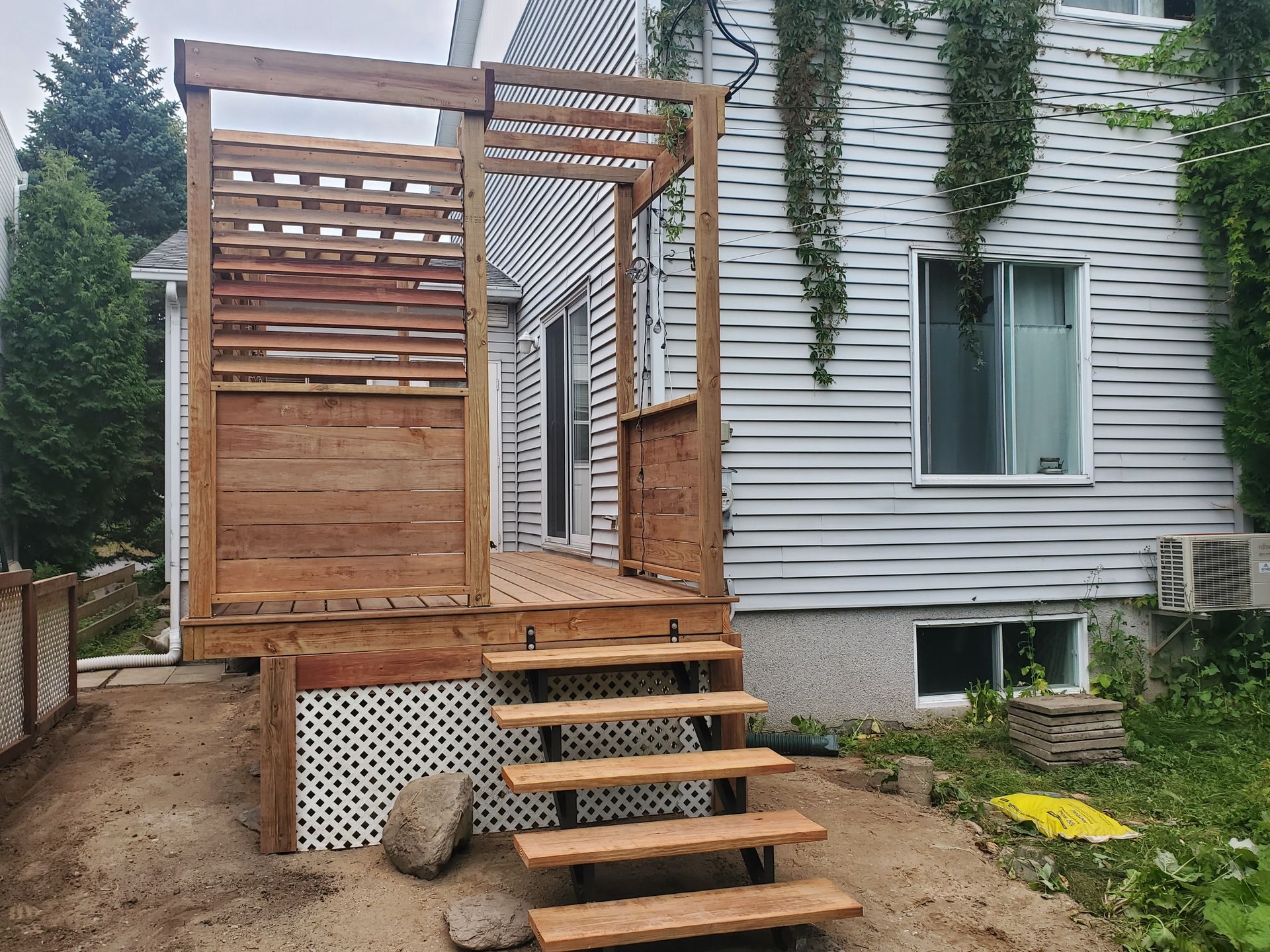 Une maison blanche avec une terrasse en bois et des escaliers devant