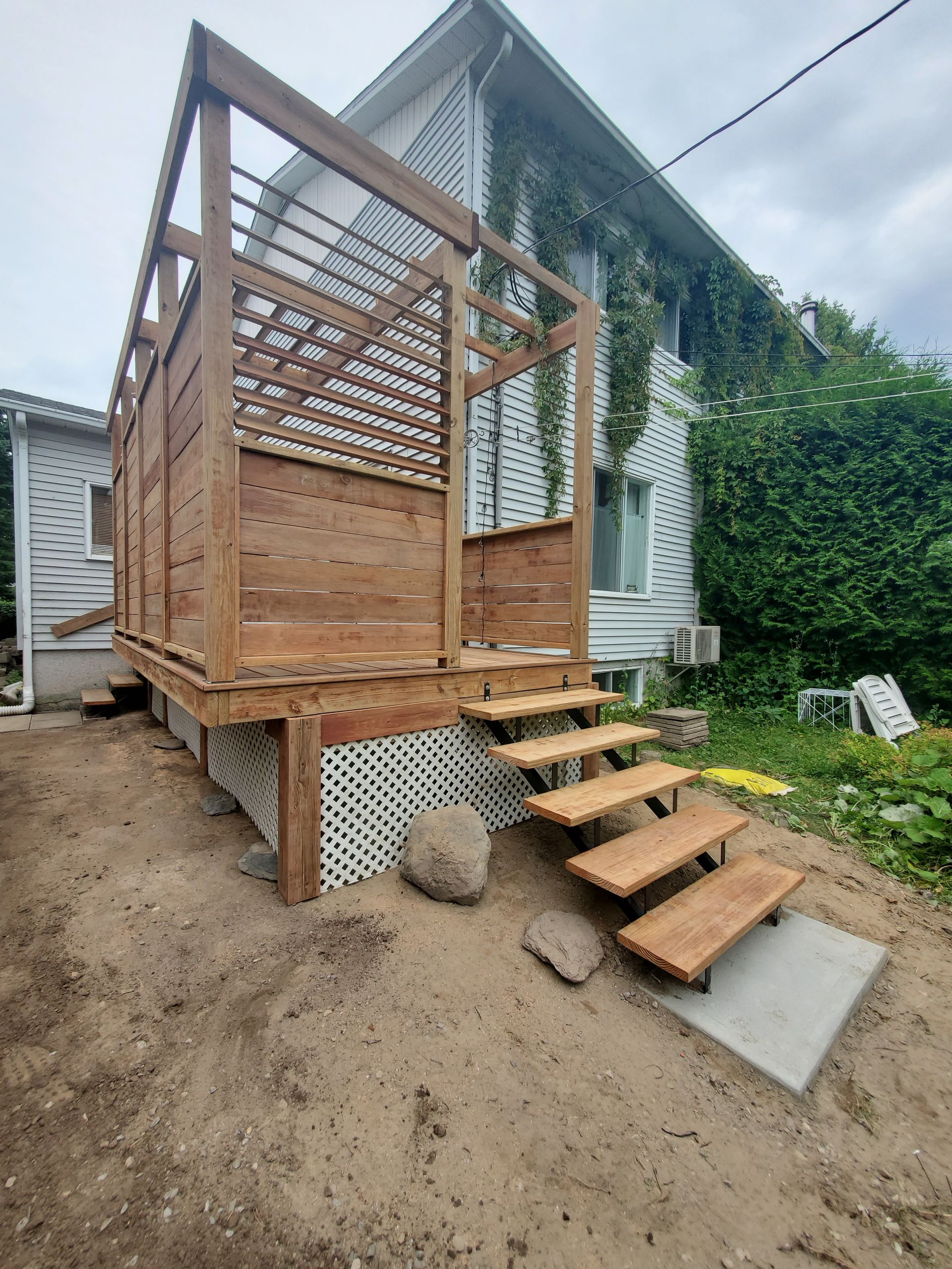 Une terrasse en bois avec des escaliers est en cours de construction devant une maison.