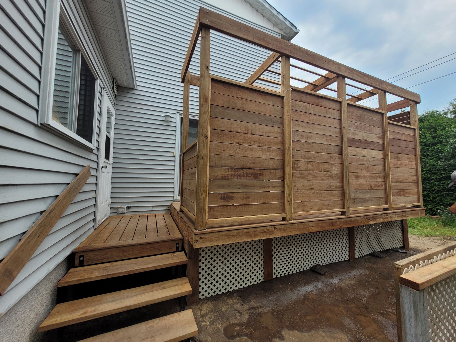 Une terrasse en bois est en cours de construction sur le côté d'une maison.