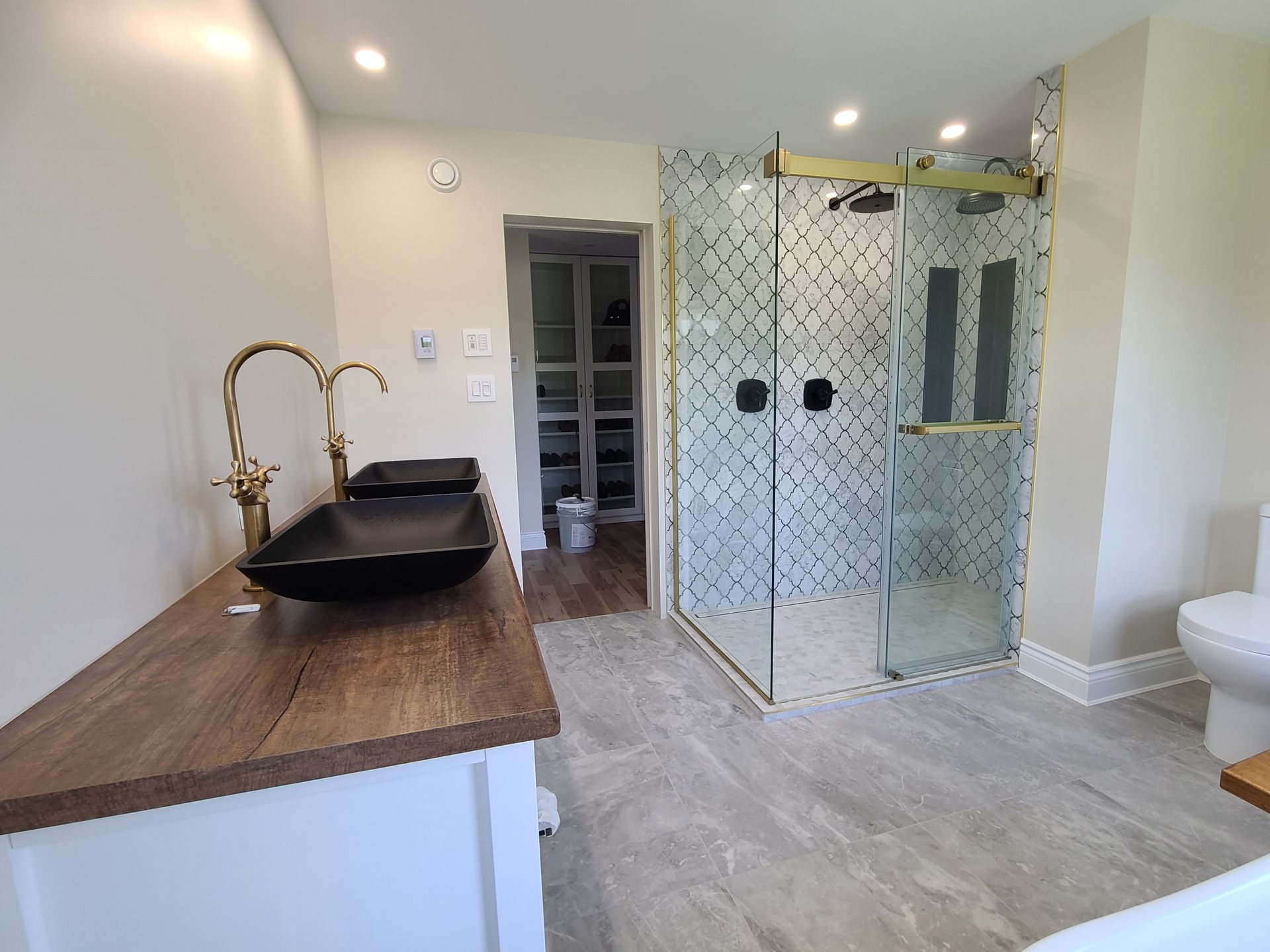 Une salle de bain avec deux lavabos, un WC et une douche à l'italienne.