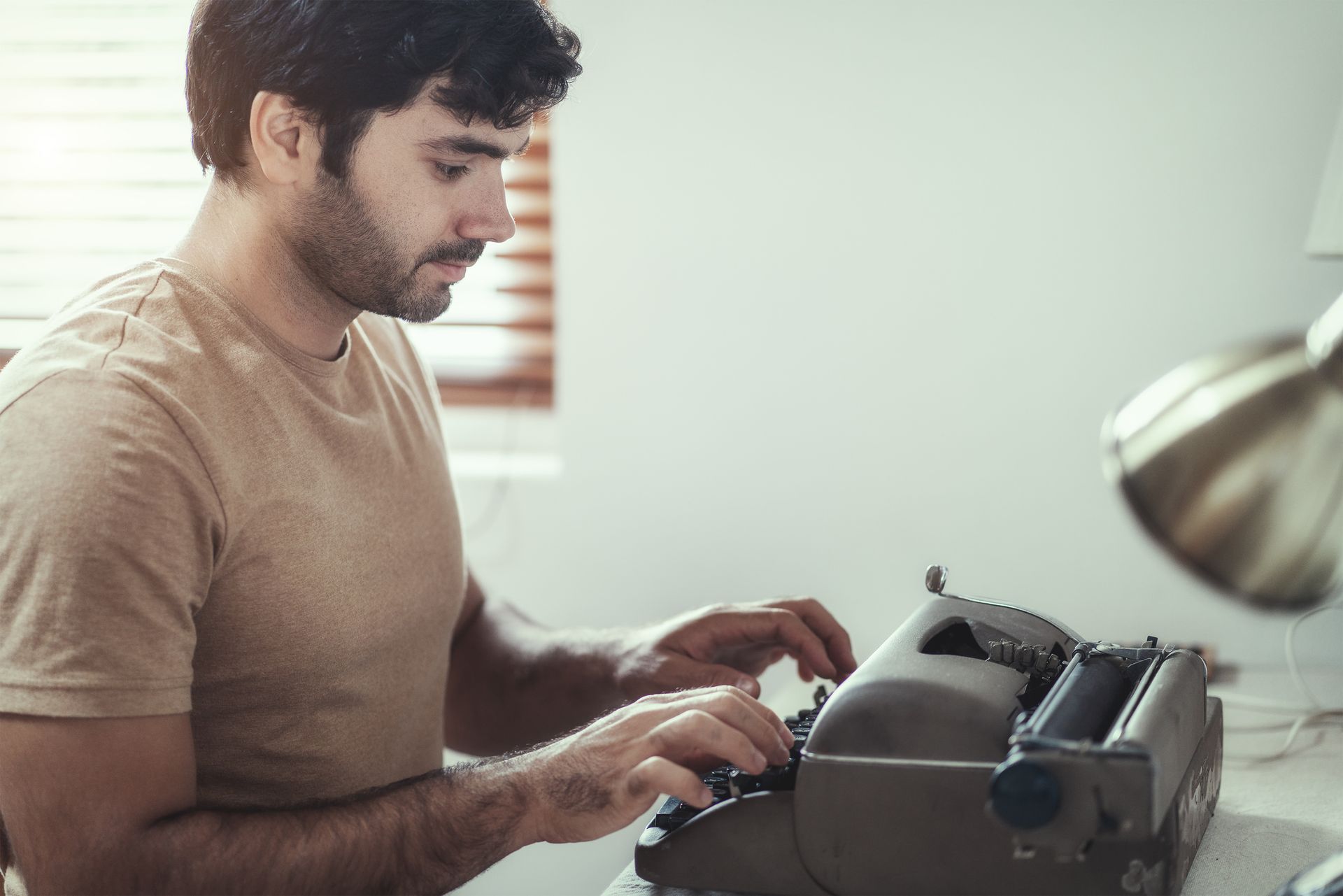 A man types on a retro typewriter in his office.