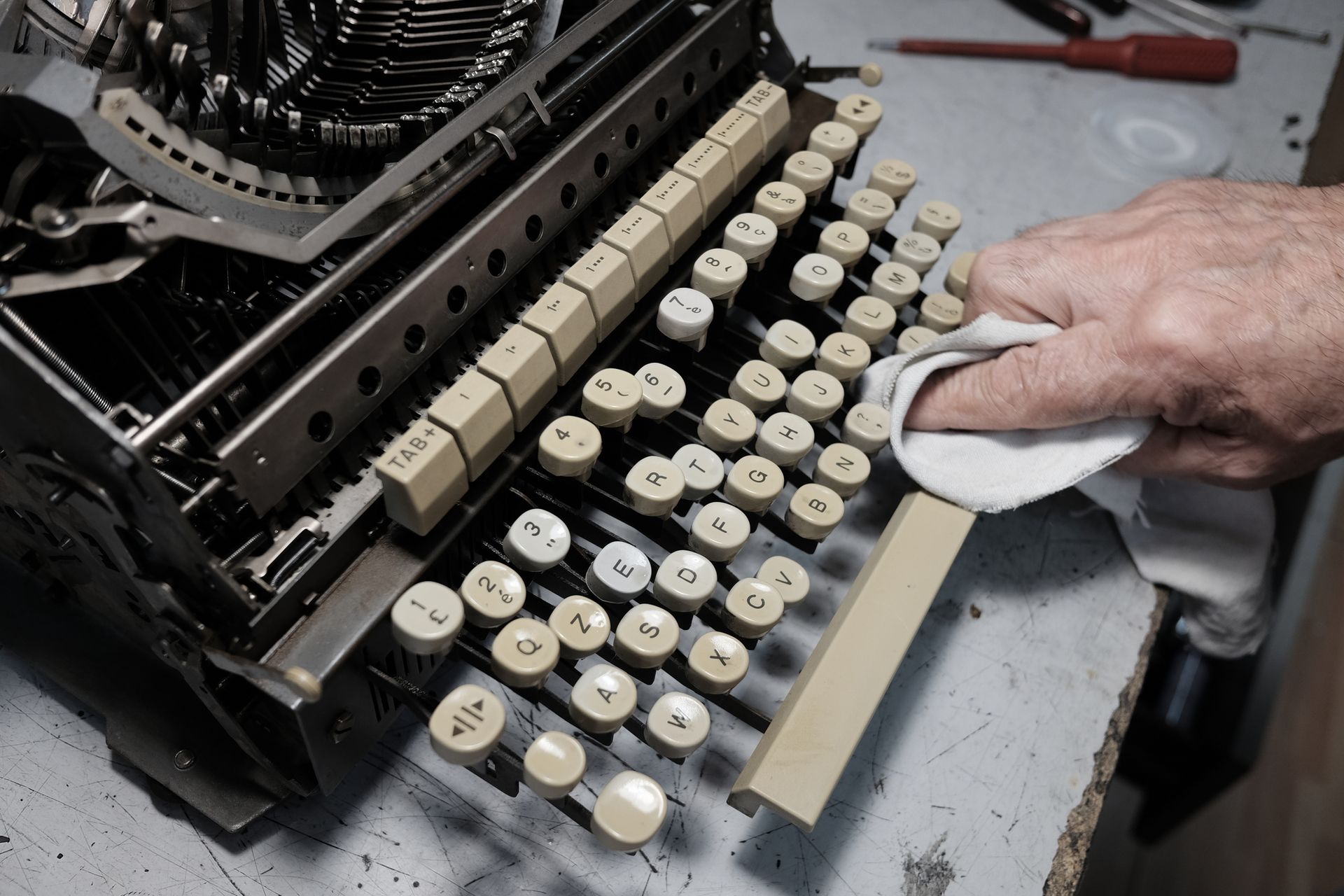 A technician does maintenance service on an old typewriter.][