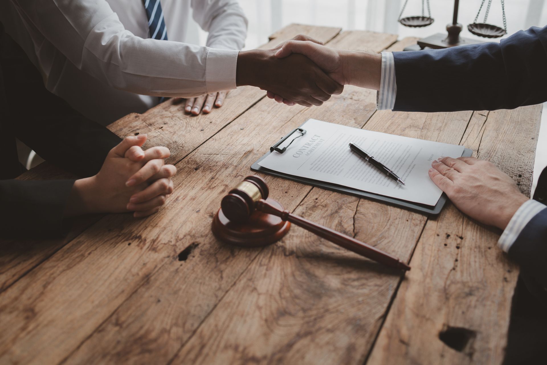 A group of people are shaking hands over a wooden table.