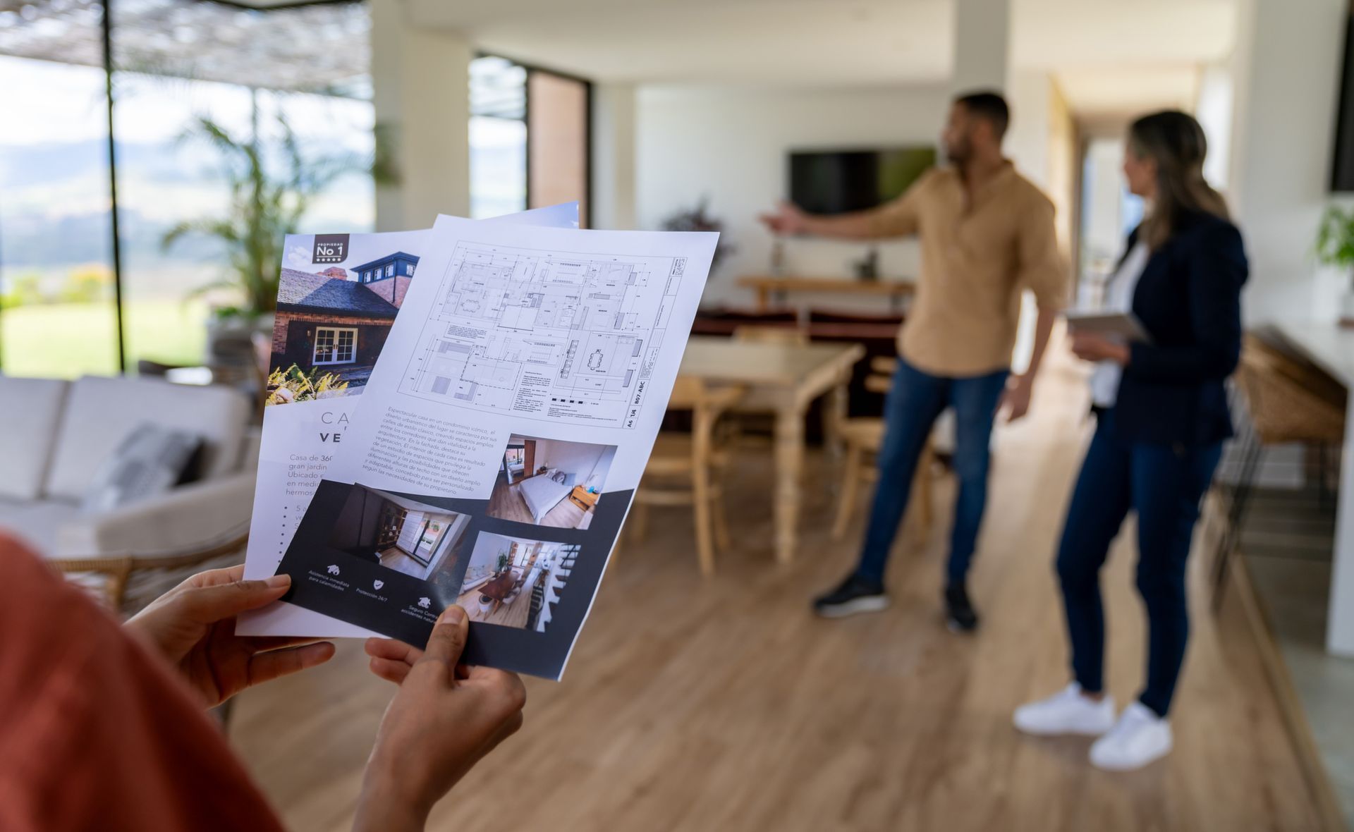 A woman is holding a piece of paper in front of a man and woman in a living room.