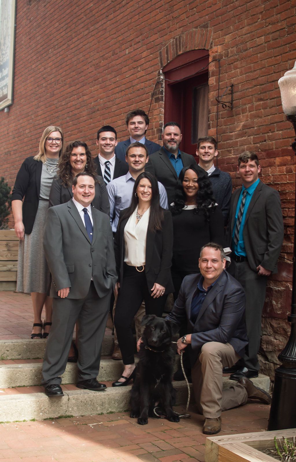 A group of people are posing for a picture in front of a brick building.
