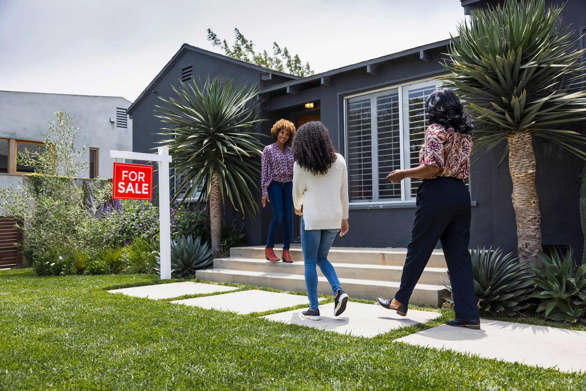 A woman is talking to a girl in front of a for sale sign.