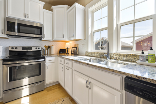 A kitchen with stainless steel appliances and white cabinets.