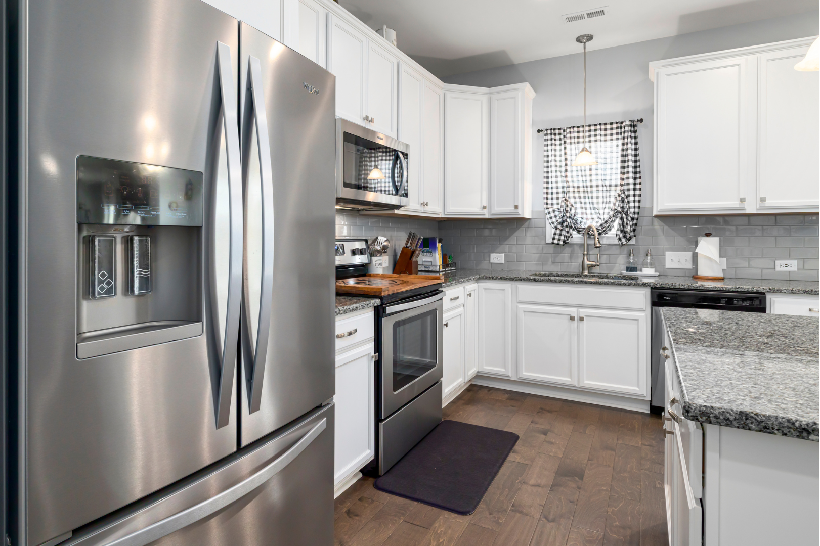 A kitchen with stainless steel appliances and white cabinets.