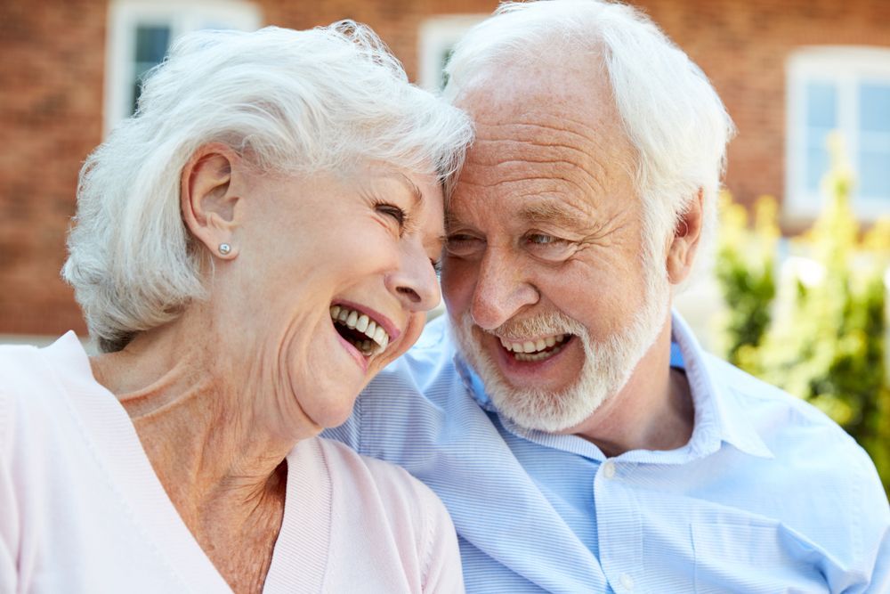 Smiling elderly couple embracing outdoors.