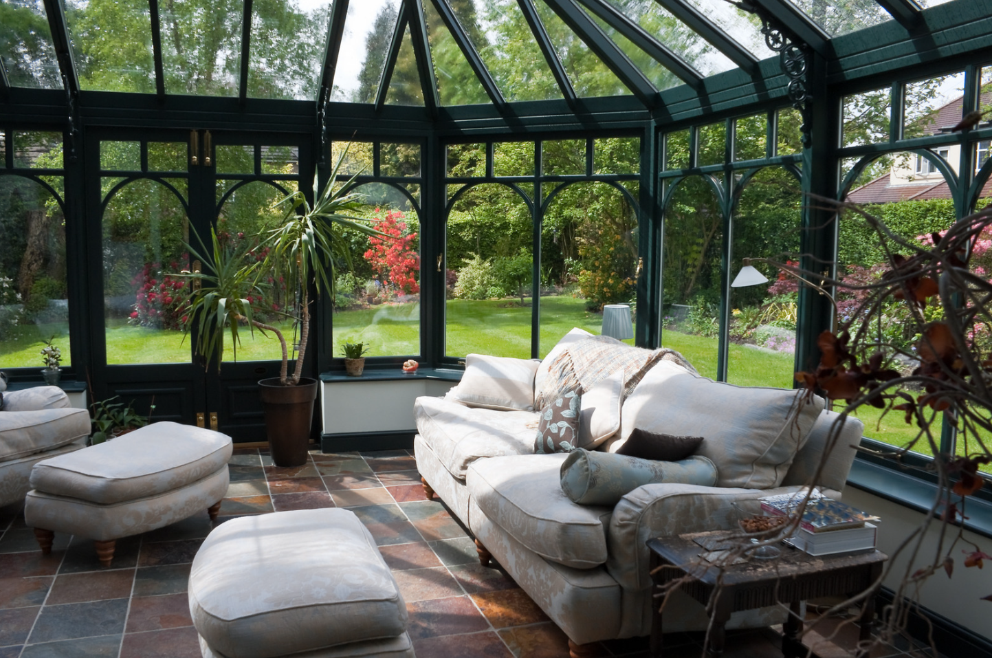 A living room with a couch and chairs in a conservatory.