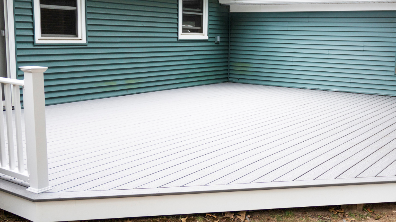A white deck with a white railing is in front of a blue house.