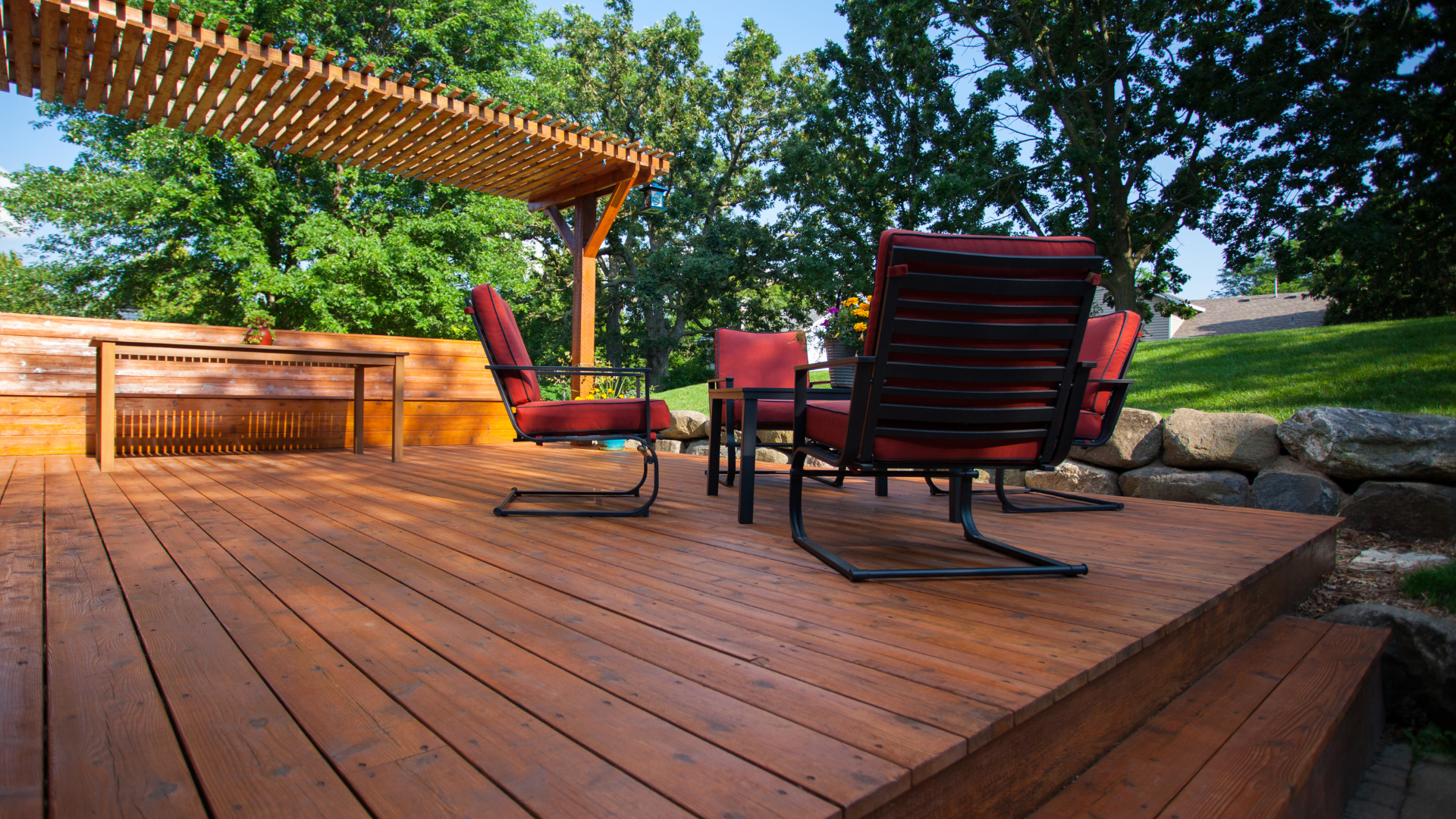 A wooden deck with chairs and a table under a pergola.