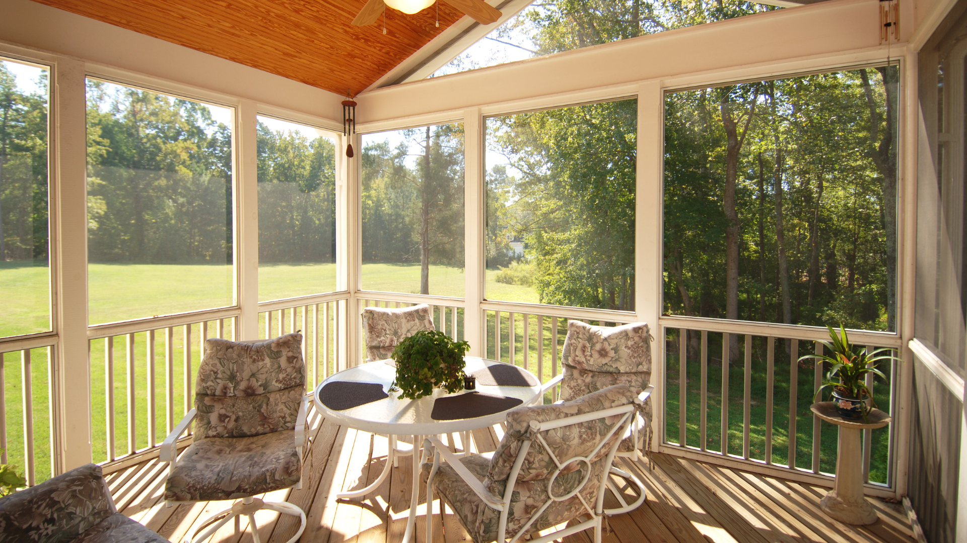 A screened in porch with a table and chairs