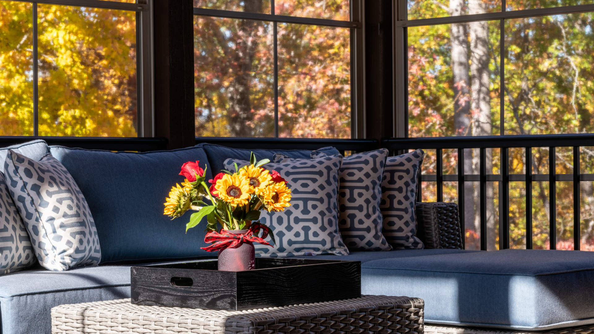 A living room with a couch and a table with a vase of flowers on it.