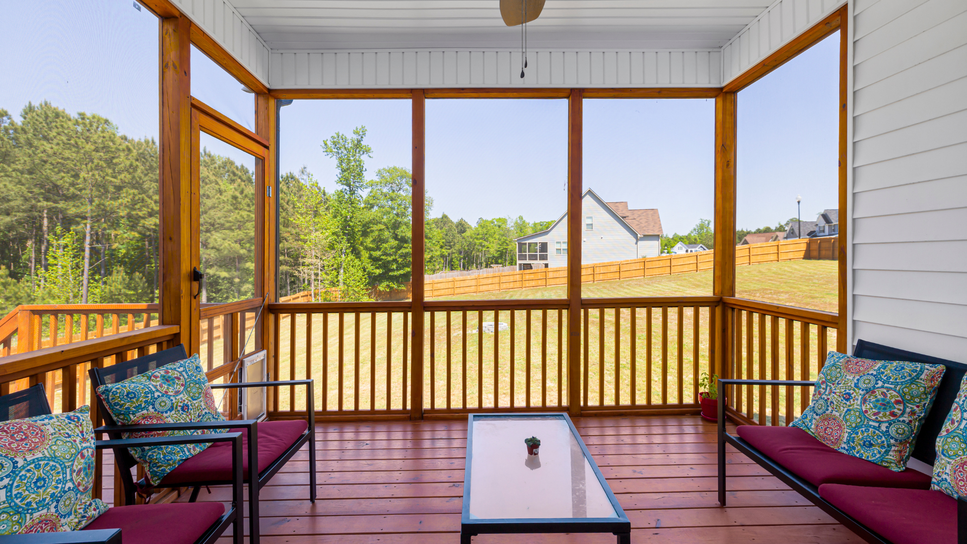 A screened in porch with furniture and a ceiling fan.