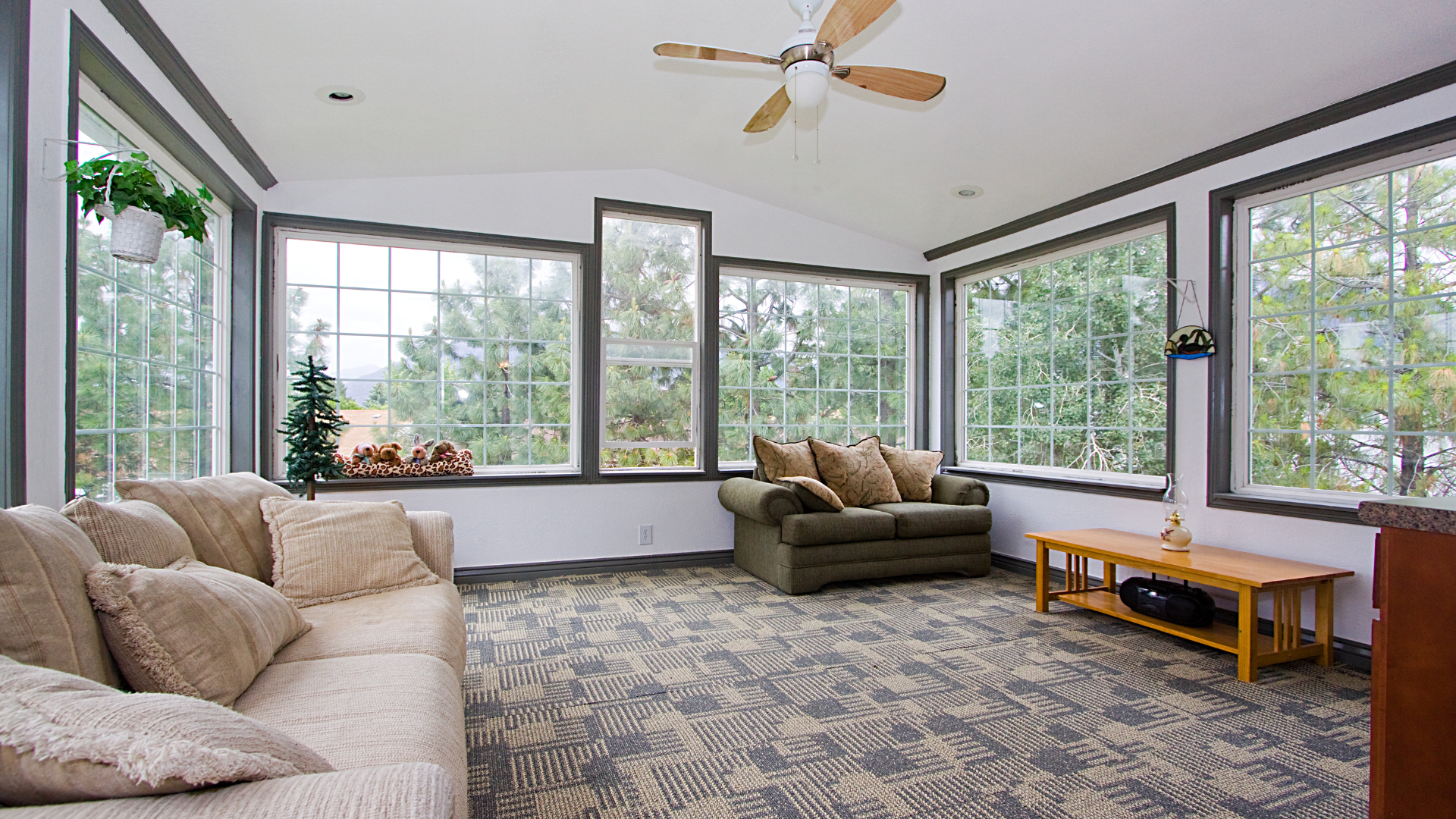 A living room with a lot of windows and a ceiling fan