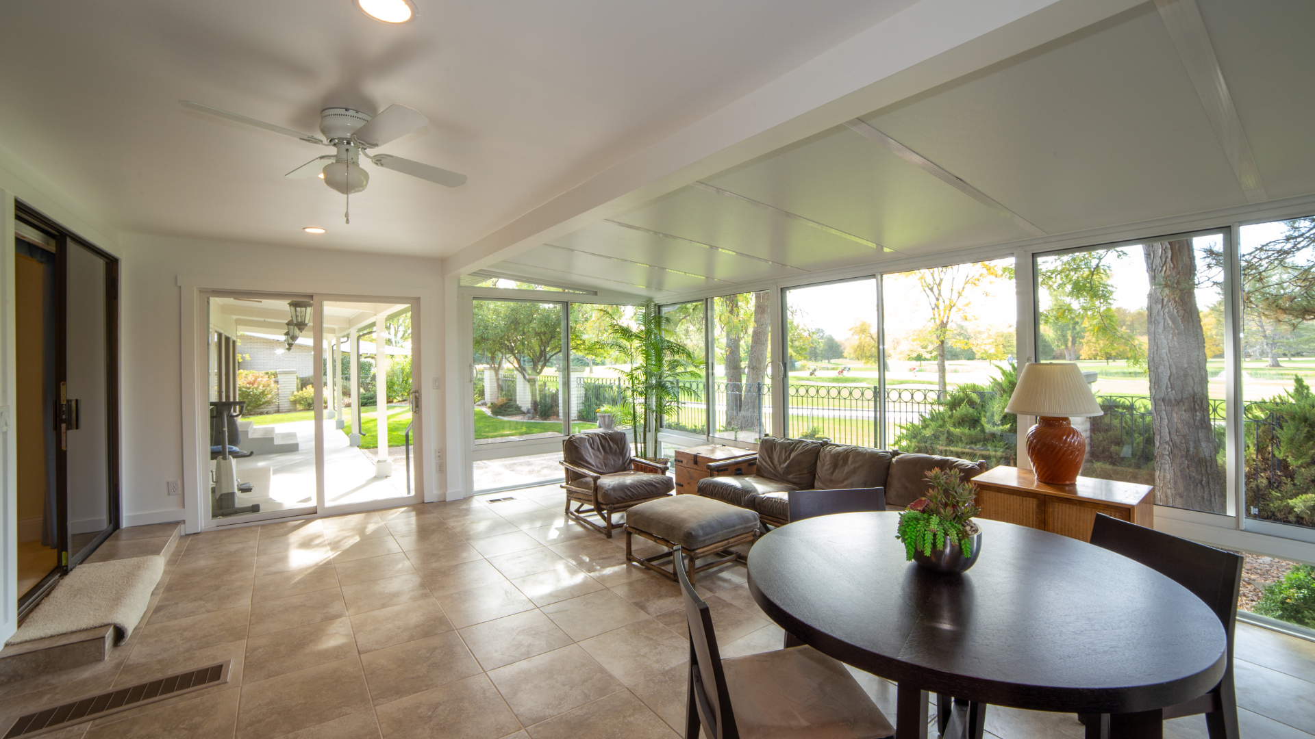 A living room with a table and chairs and a ceiling fan.
