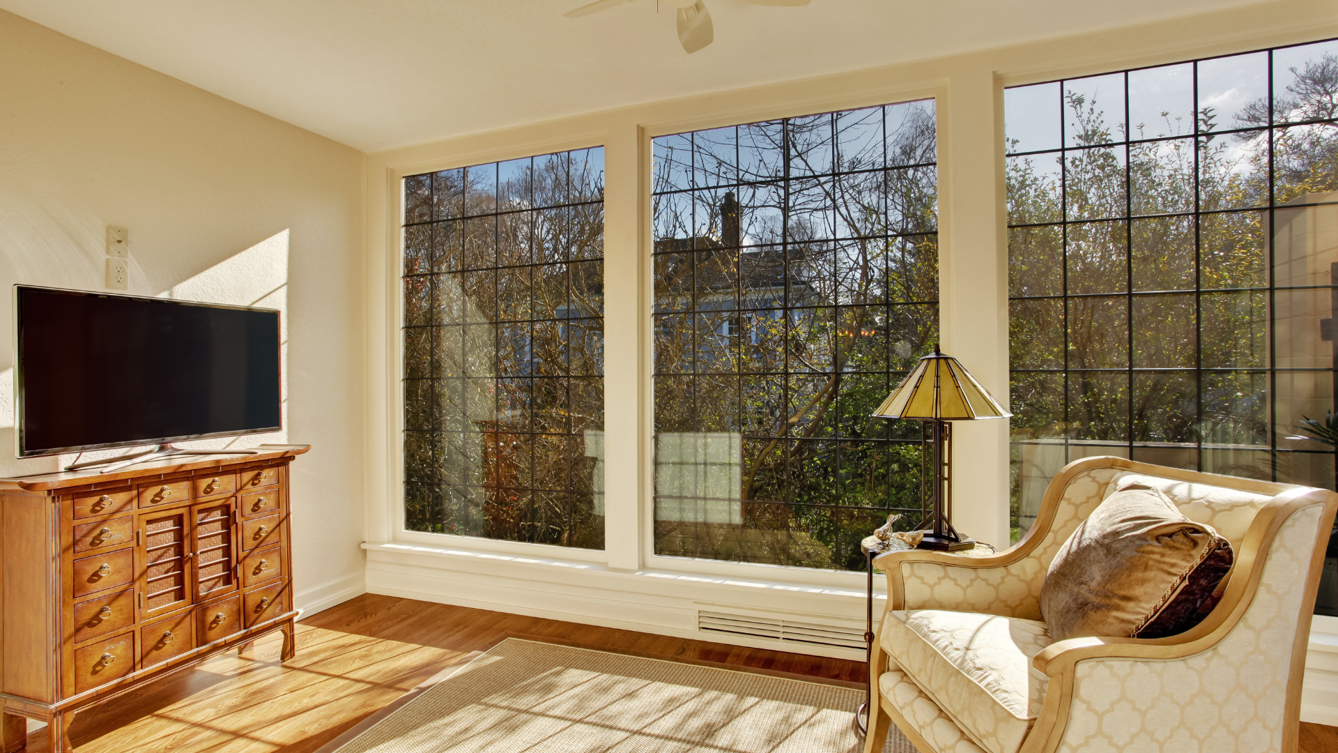 A living room with a chair , television , and large windows.